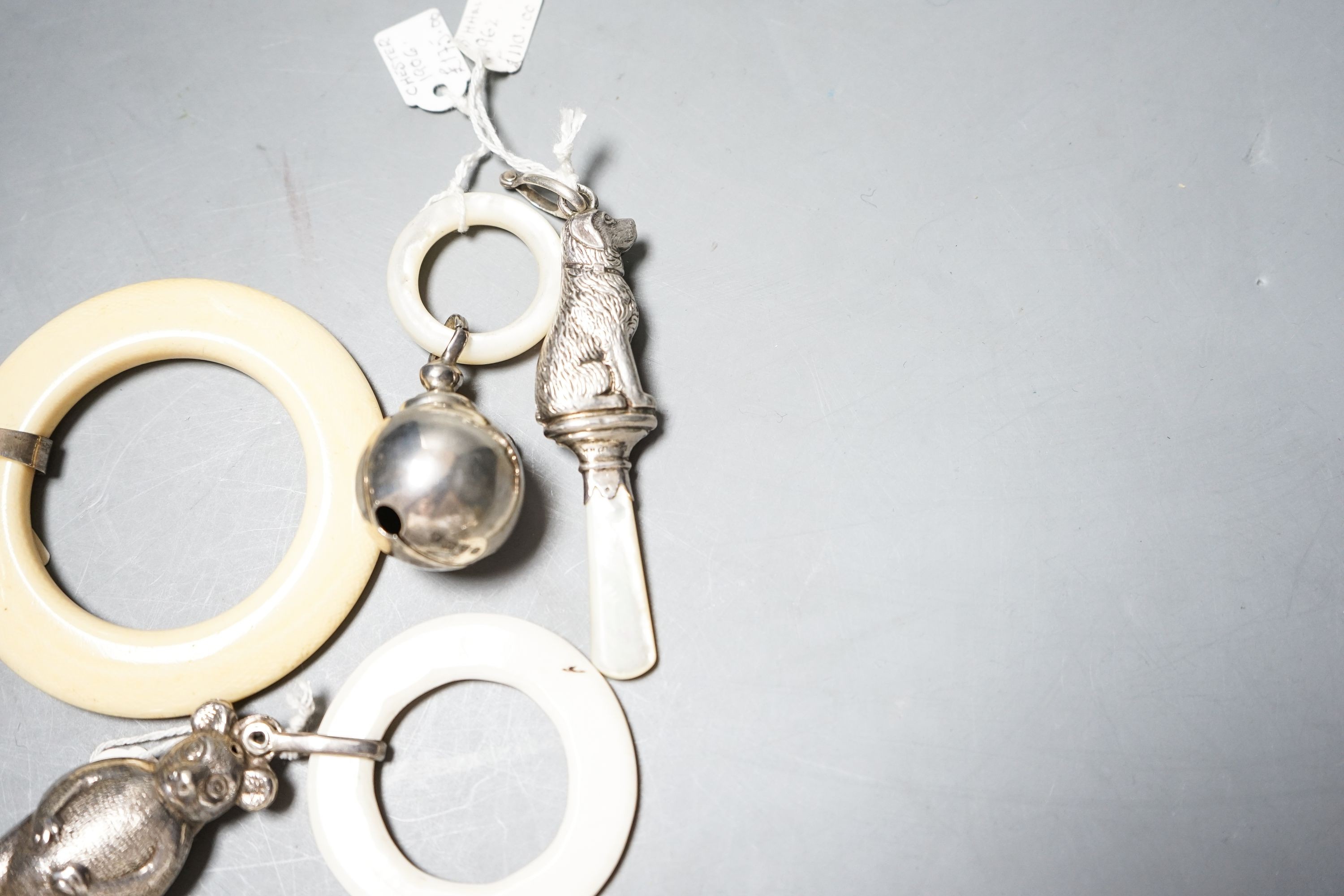 Four assorted child's silver and white metal teething rattles, including dog, bear and acorn.